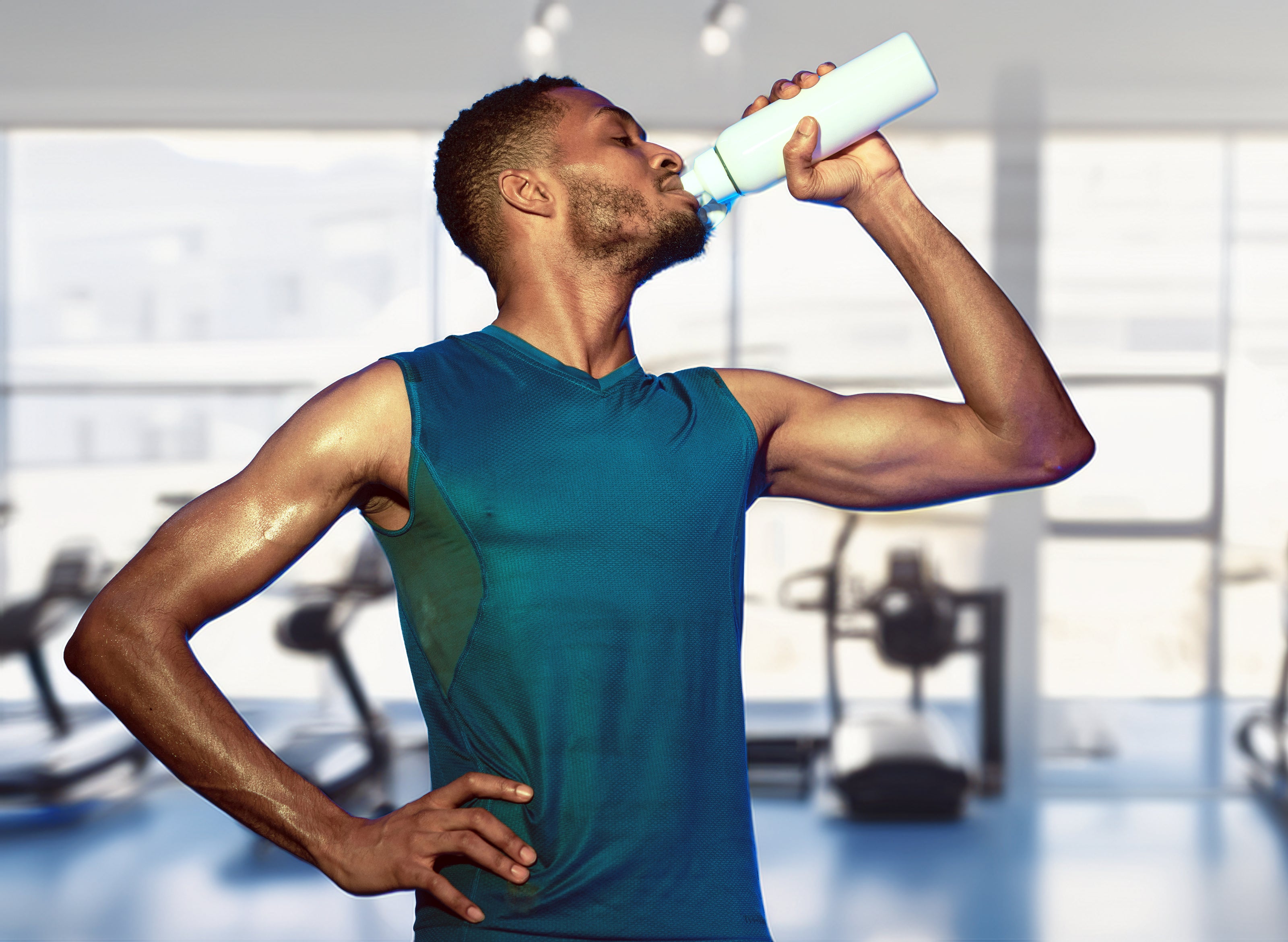 Man in a gym drinking from a water bottle